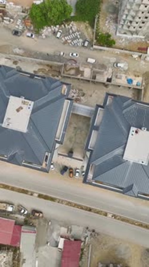 Vídeo vertical: una vibrante escena de construcción captura el acristalamiento de balcones, trabajos de fachada y cimientos