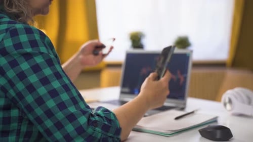 Woman Holding Phone and Credit Card at Desk
