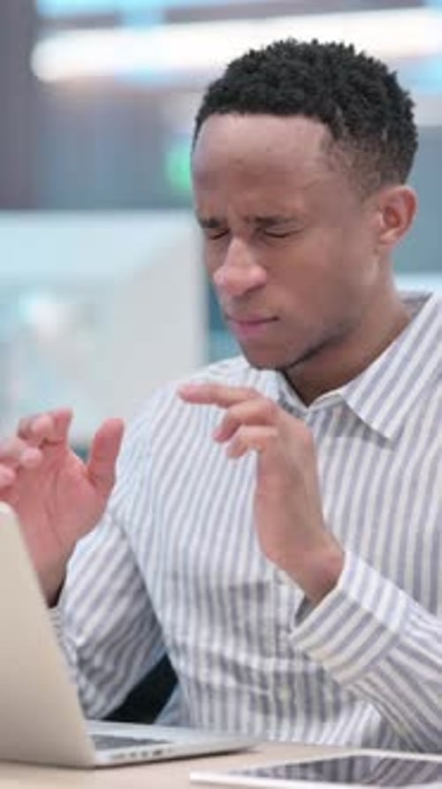 Young Adult Man with Headache Massaging Temples at Desk