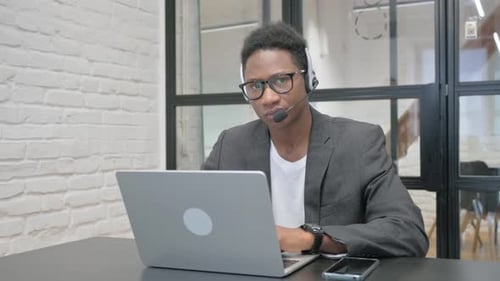 Young Adult Working at Laptop with Headset
