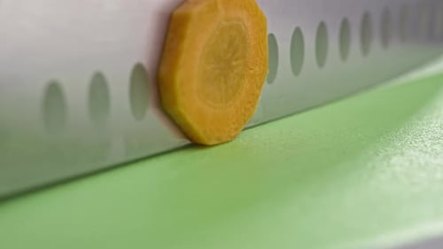 Knife Slicing a Carrot on Cutting Board