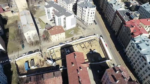 Aerial drone rotating shot over a construction site surrounded by rows of terraced houses on a brigh