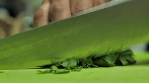 Sharp Damascus steel blade knife cut fresh parsley, close up