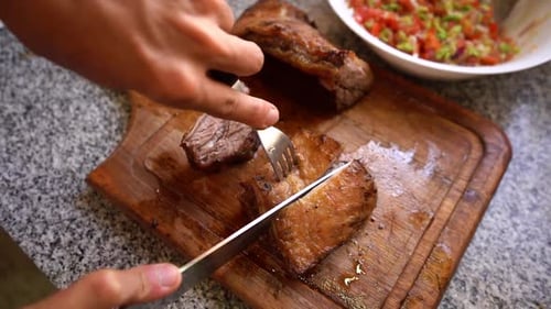 Chef rebanando jugosa carne asada en una tabla de madera con ensalada