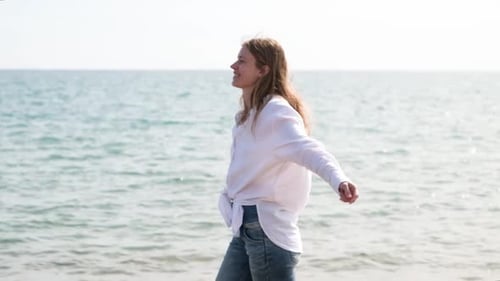 Summer vacation, young adult woman in white linen shirt walking on sea beach