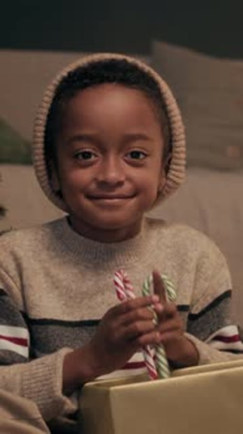 Smiling Child Holds Candy Canes and Christmas Gift