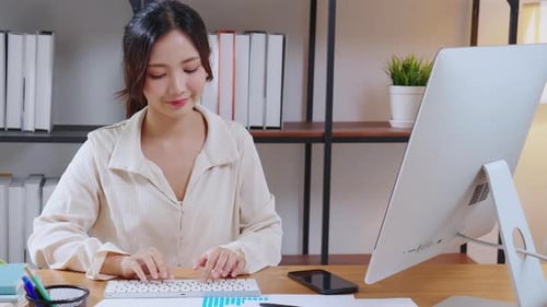 Woman Thinking and Typing at Computer in Office
