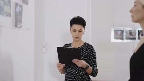 A Woman Gallery Owner Tells Visitors About the Paintings Presented at the Exhibition