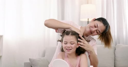 Woman Styling Young Girl's Hair Indoors