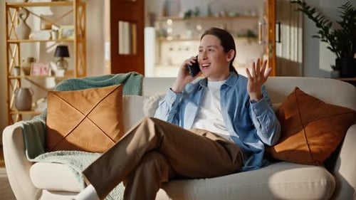 Man chatting animatedly on phone, relaxing on sofa