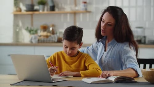 Mother Helping Child With Homework in Kitchen