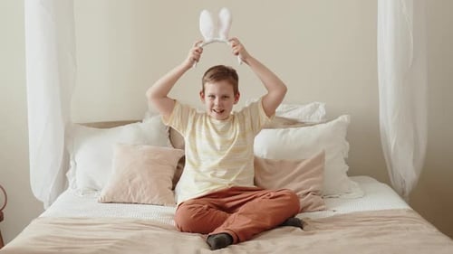 Smiling Child Wearing Bunny Ears on Bed