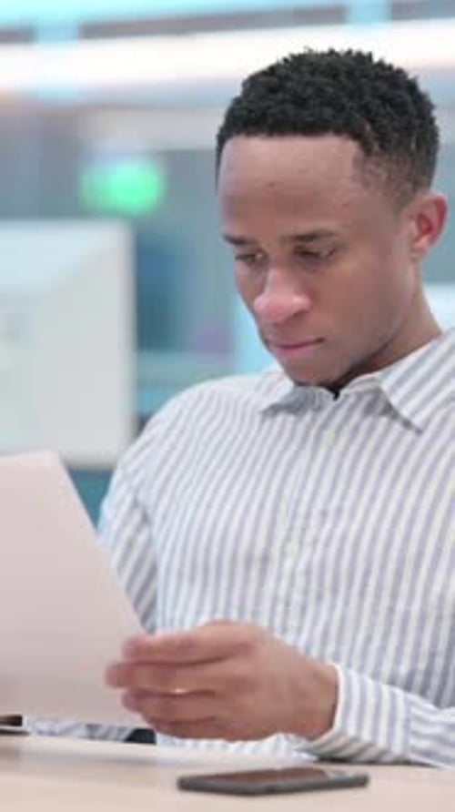 Excited Young Adult Man Celebrates Success with Documents