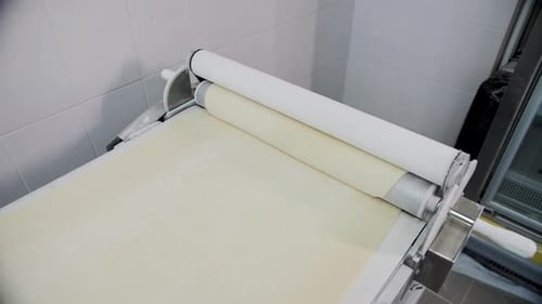 Automated Dough Sheeter Machine Rolling Pastry in a Commercial Bakery