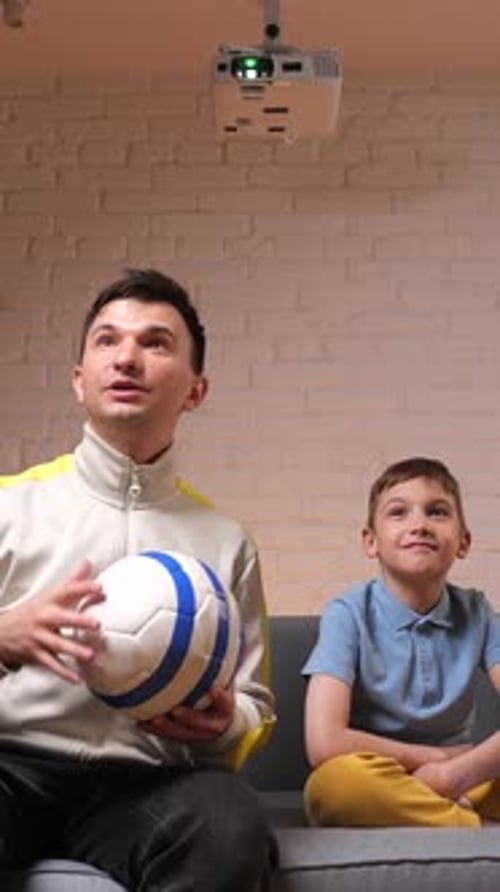 Father and Son Watching a Game on Projector