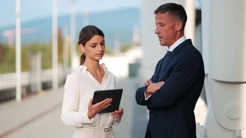 Two business people communicate with each other standing near office building