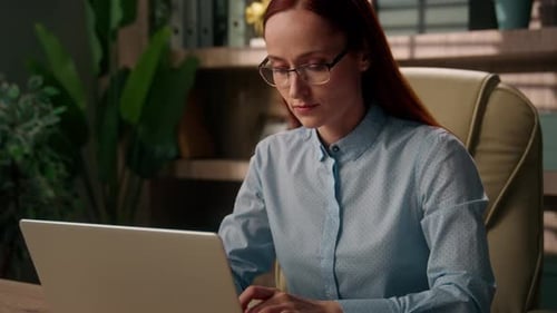 Woman Working on Laptop at Desk in Office