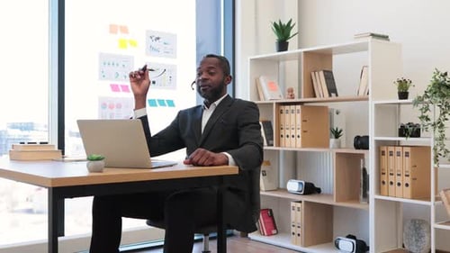 African Man in Headset Using Laptop for Video Call at Office