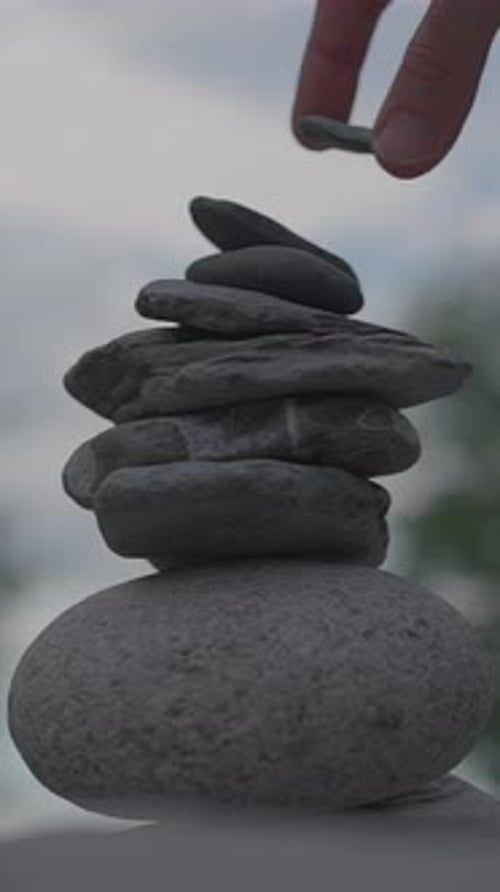 Hand Adding Rock to Balanced Cairn
