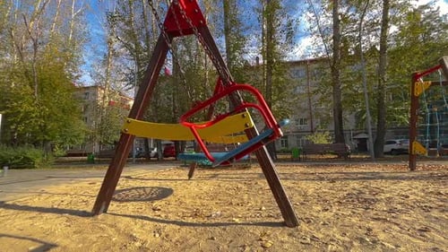 Empty Swings Waiting on Children in Playground on Sunny Autumn Day
