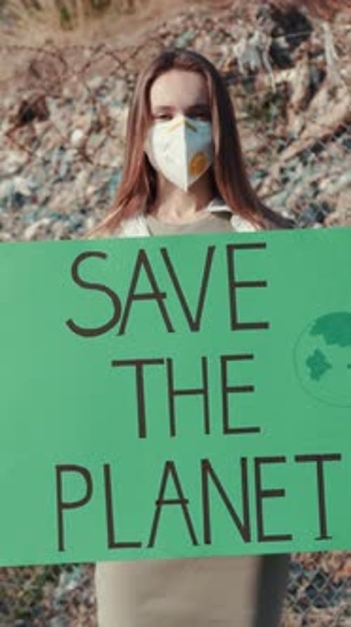 Woman Holds Save the Planet Sign Near Landfill