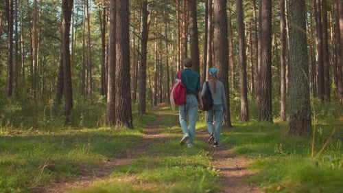 Sisters Walking Through Lush Green Forest with Backpacks and Blue Hair Tie
