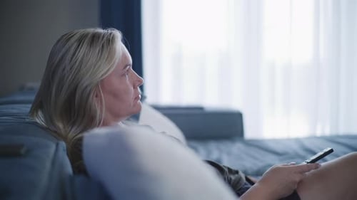 Woman Relaxes on Couch with Remote Control
