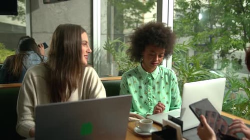 Millennial female workers doing remote work at cafe. Young entrepreneurial women in collaboration