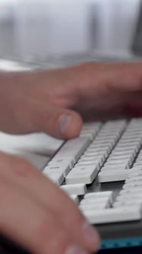 Des mains masculines concentrées tapant rapidement sur un clavier d'ordinateur élégant