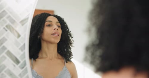 Woman with Curly Hair Styling Herself in Mirror