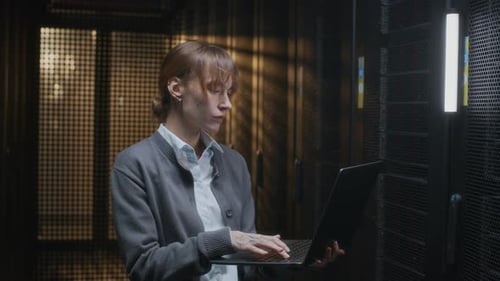 Young Adult Working with Laptop in Server Room