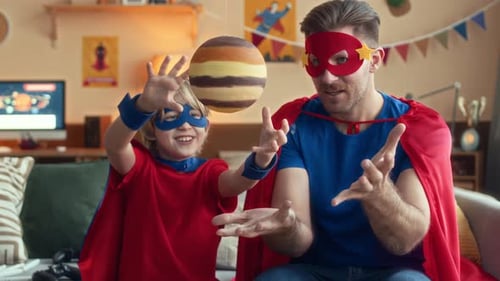 Father and Son Wearing Superhero Costumes Indoors