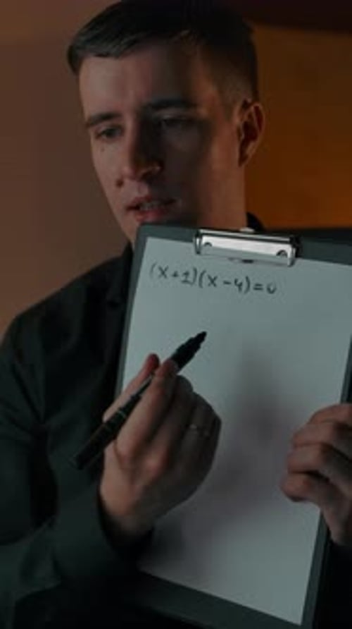 Young Adult Man Drawing Math Equation on Clipboard