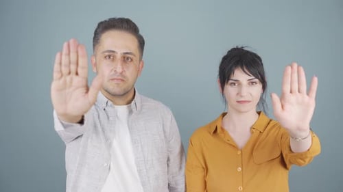 Paar schaut in die Kamera und macht ein Stoppschild.