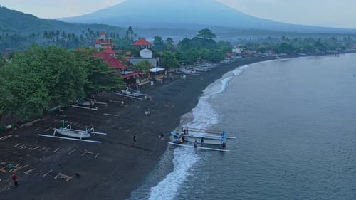 Vista aérea de pescadores lanzando un bote jukung desde una playa amada con el monte Agung