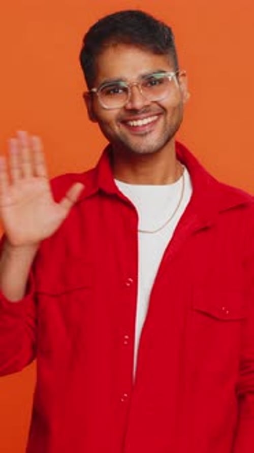 Smiling young man waving his hand in greeting