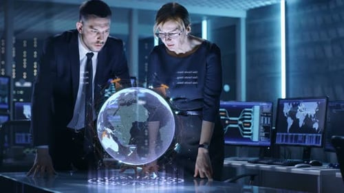 Agentes masculinos y femeninos utilizan una mesa holográfica de medios mixtos para la vigilancia por satélite. En el monitor