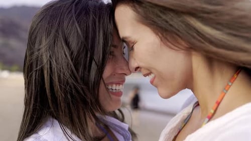 Gay lesbian female couple enjoy tender moment together outside with beach background. LGBTQ