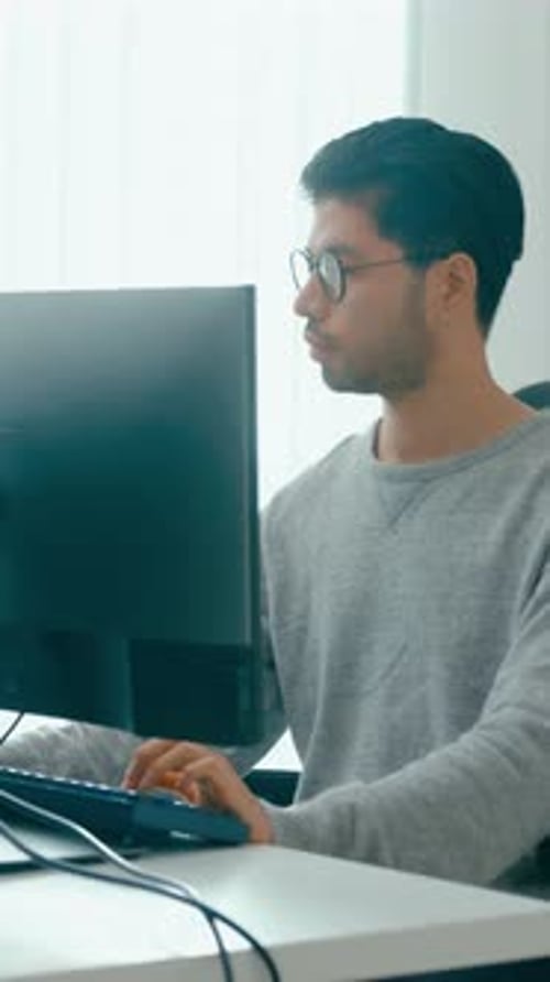 Lunettes de vue indépendantes pour hommes asiatiques pour jeunes adultes dactylographiant un codage AI rapide sur un ordinateur de bureau.