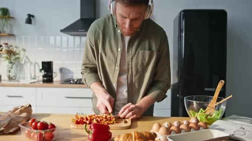 Young Man Cooking with Vegetables in Kitchen