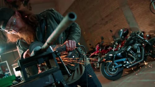 Creative authentic motorcycle workshop redhead bearded brutal biker works with circular saw Sparks