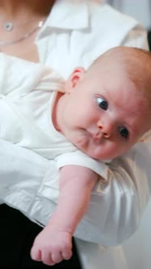 Lovely red-haired newborn in mom's hands. Calm baby boy with his parents at home. Close up.