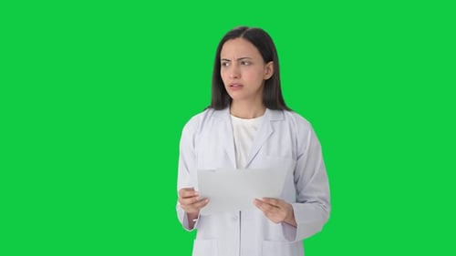 Stressed Indian female scientist reading reports Green screen