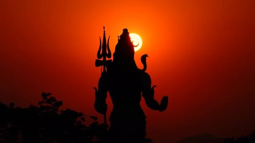 Concentration sur la silhouette de Lord Shiva au lever du soleil dans le ciel orange de Haridwar.