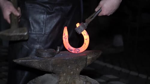 Blacksmith Shaping Glowing Horseshoe on Anvil at Night