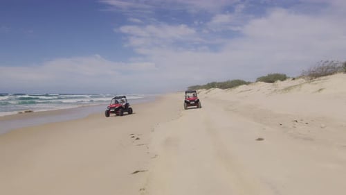 Two ATV Vehicles Racing on a Beautiful Beach with Ocean and Open