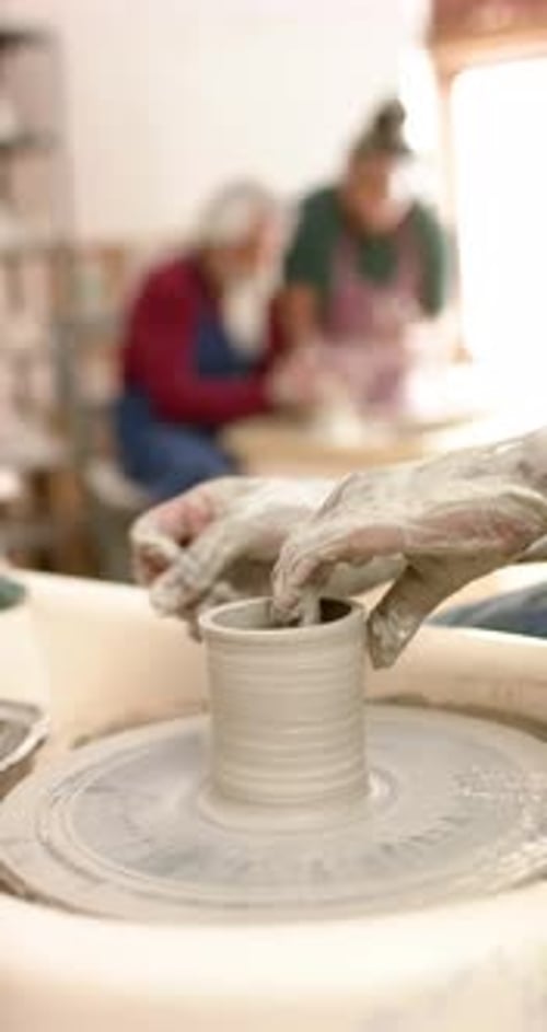 Mains d'un potier afro-américain utilisant un tour de potier dans un atelier de poterie, Ralentissement
