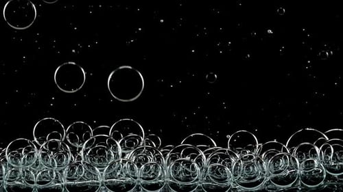 Foto macro de bolhas de ar transparente de tamanhos diferentes em água limpa subindo sobre o corpo de fundo preto