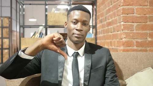 Man Gives Thumbs Down in Office Setting