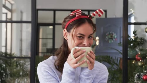 Smiling Woman with Christmas Headband Holding Mug